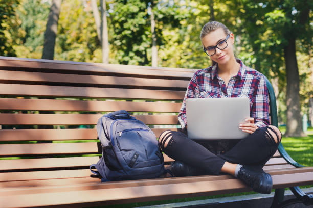 istock Young woman using laptop in park, copy space 918537660