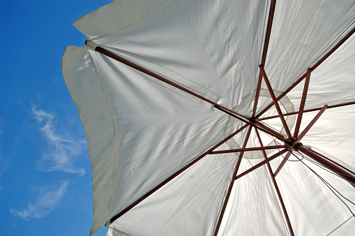 A parasol blocks the sun's rays with clouds high up.