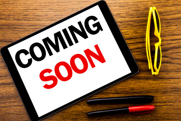 istock Writing text showing Coming Soon. Business concept for Message Future Written on tablet laptop, wooden background with vacation yellow glasses and marker pen. 918549582