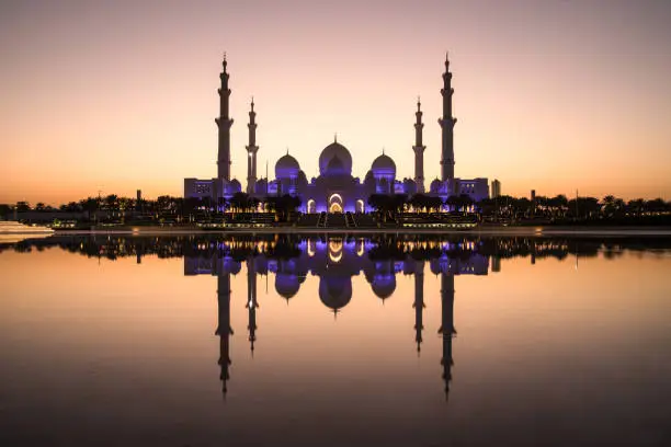 Sheikh Zayed Grand Mosque and it's perfect reflection in a water pool during dusk after sunset. Abu Dhabi, UAE.