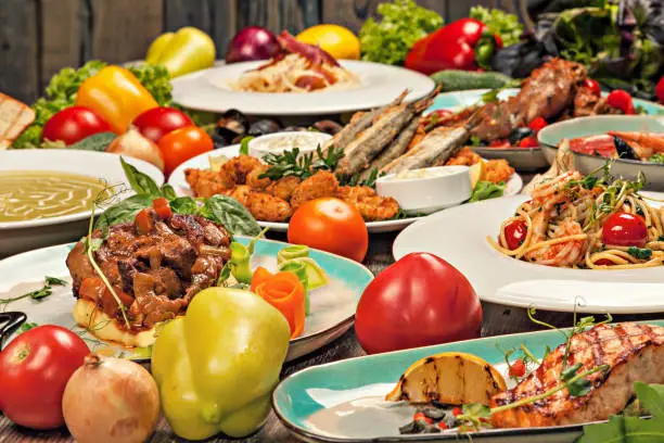 Set of various dishes of italiancuisine, vegetables and herbs on a wooden table.