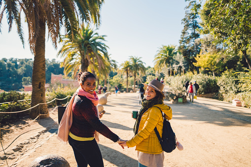 Two friends holding hands and smiling back to the camera