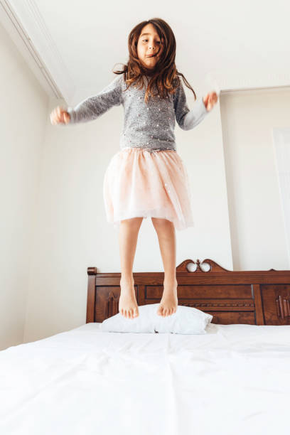 istock Little Girl Jumping On Bed 918556316