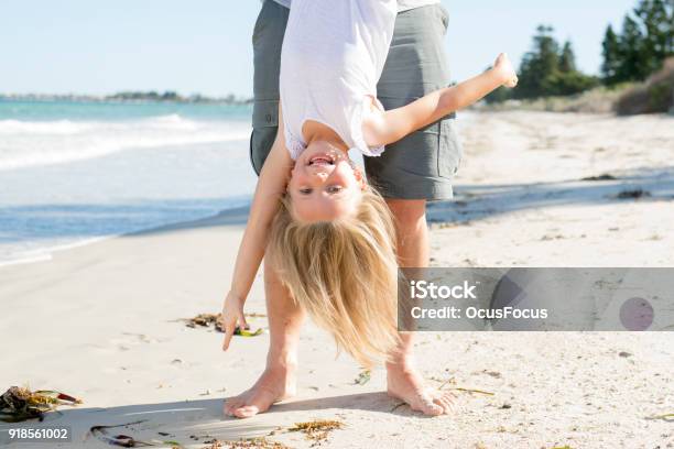 Father Holding Sweet Young And Lovely Blond Small Daughter By Her Feet Playing Having Fun On The Beach In Dad And Little Girl Love Concept Enjoying Summer Holidays Stock Photo - Download Image Now