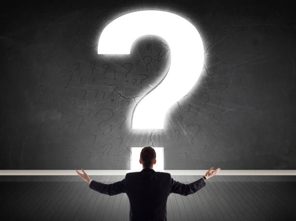 istock Business man looking at wall with a bright question mark 918565940