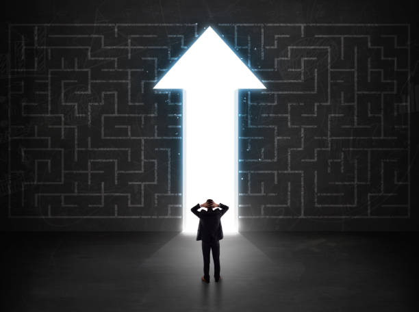 istock Business person looking at maze with solution arrow on the wall 918566024