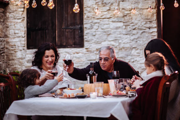 diversión familiar y brindando con bebidas en mesa de comedor - los niños y los padres brindis bebidas mientras almuerza fotografías e imágenes de stock