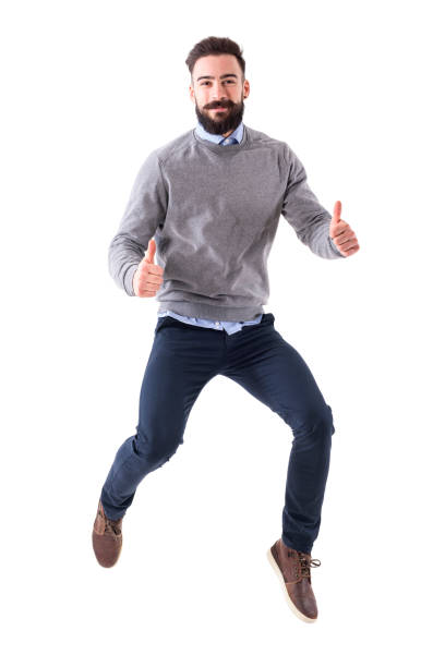 Joyful excited business man jumping with thumbs up gesture smiling at camera stock photo