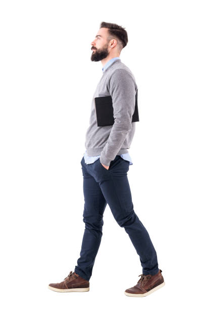 istock Confident serious businessman walking and carrying planner under arms. Side view. 918569746