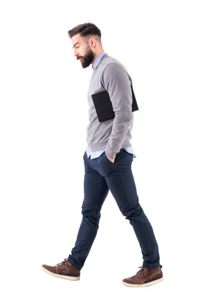 istock Thoughtful young businessman carrying notebook under the arm walking and looking down. 918569794