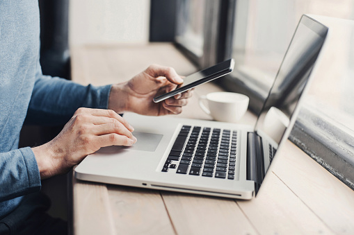 Men student is typing on laptop computer and using smartphone