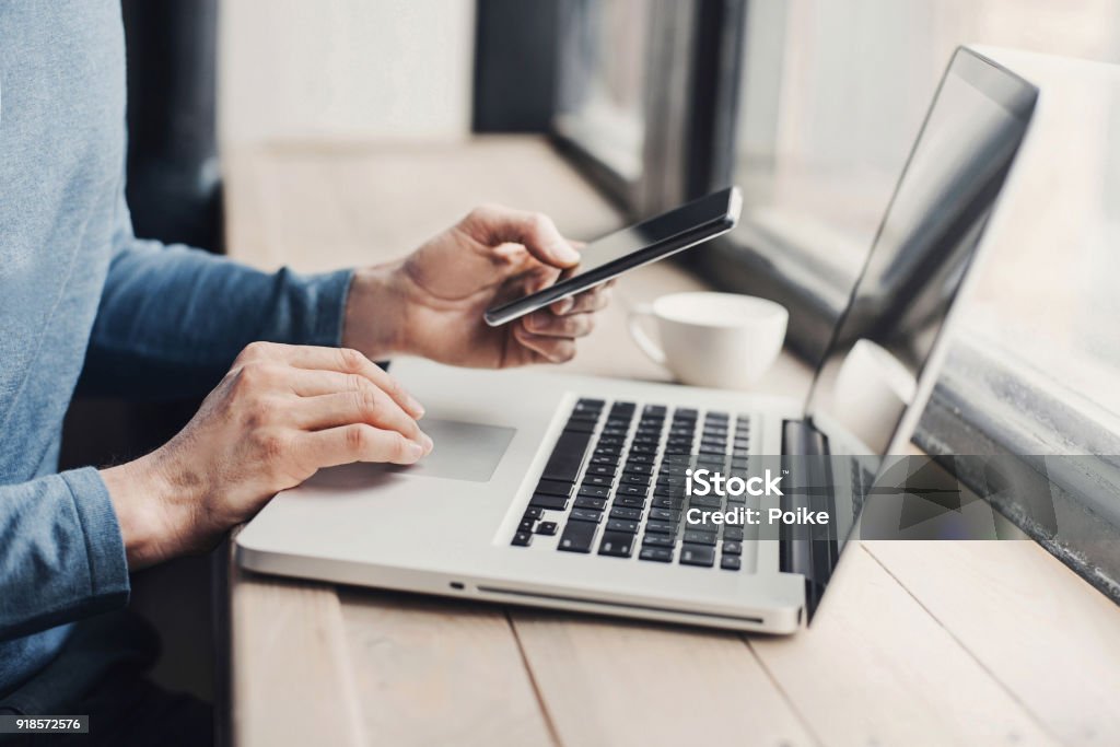 Young man using laptop computer and smart phone Men student is typing on laptop computer and using smartphone Laptop Stock Photo