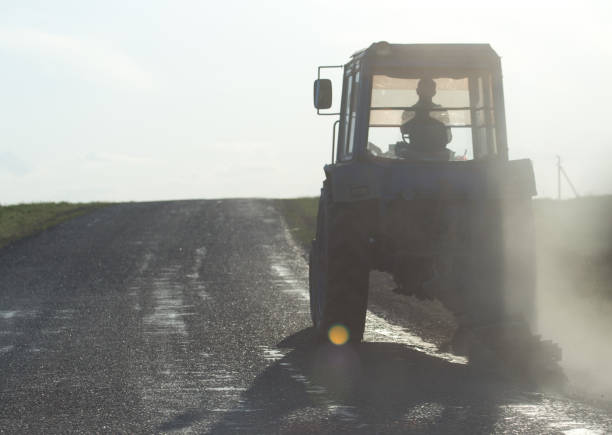 istock tractor on the road at sunset 918575904