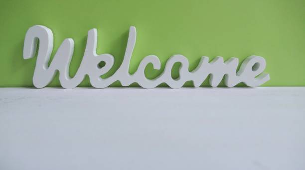 istock White wooden word Welcome on green background 918579732