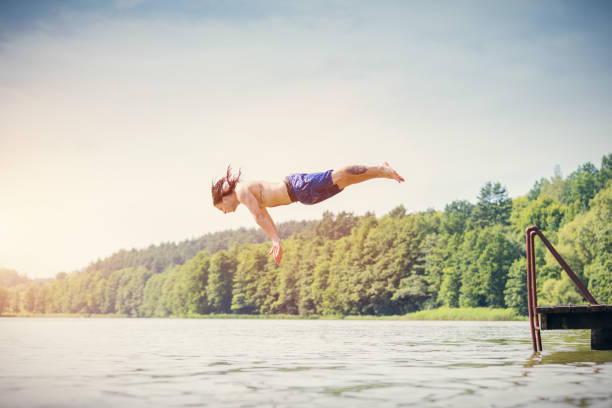 istock Young fit man making a jump into a lake. 918582950