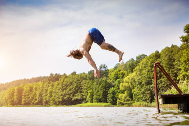 istock Young fit man jumping into a lake 918582952