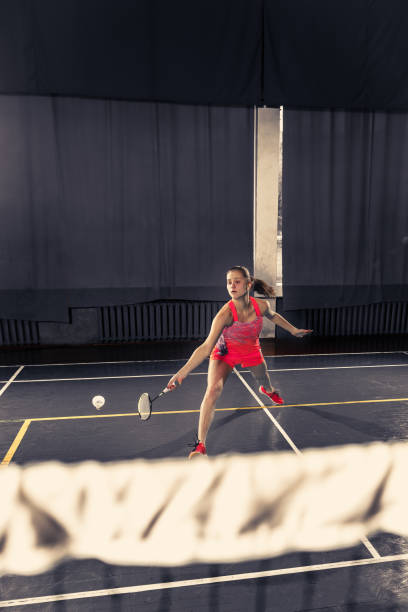 jovem mulher jogando badminton no ginásio - badminton school gymnasium shuttlecock sport - fotografias e filmes do acervo