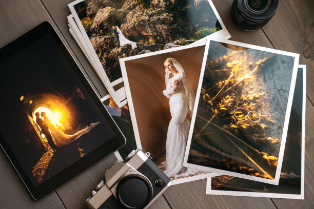 Printed wedding photos with the bride and groom, a vintage black camera and a black tablet with a picture of a wedding couple Printed wedding photos with the bride and groom, a vintage black camera and a black tablet with a picture of a wedding couple, on wooden background printing out photos stock pictures, royalty-free photos & images