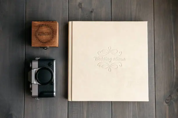 White leather wedding album, wooden box with inscription Wedding day and vintage photo camera. On wooden background