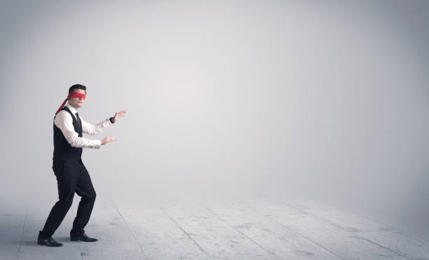 Businessman with blindfolds A young male business person in elegant dress standing with red blindfolds in a clear, empty space concept. red blindfold stock pictures, royalty-free photos & images