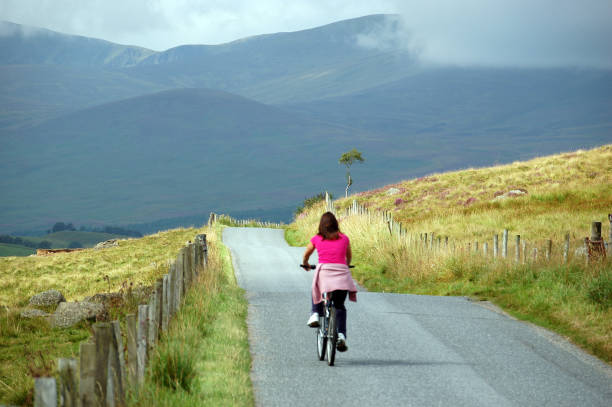 Back of young women in pink biking in the Scottish montains.