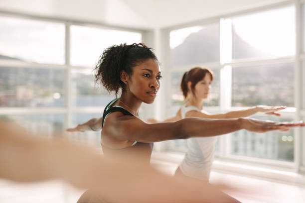 Women doing stretching and yoga workout at gym Women doing stretching and yoga workout at gym. Female trainer with her student during physical training session. differential focus stock pictures, royalty-free photos & images