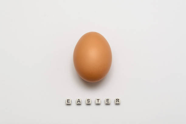 istock Chicken egg of light brown color on a white background with an Easter inscription from cubes 918625708