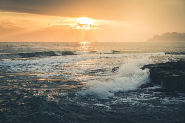 istock Golden sunset over a wavy sea on a mountain coast 918628556