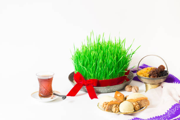 Novruz national Azerbaijan holiday spring new year celebration concept, wheat grass semeni pear shape glass of tea, traditional pakhlava shekerbura with dry fruits, vintage jar, silk scarf kelagai on white isolated background