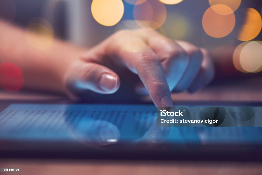 Woman reading online news on digital tablet Woman reading online news on digital tablet, close up of hands using device E-Reader Stock Photo