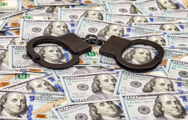 Steel black handcuffs lying on the background of american dollars Steel black handcuffs lying on the background of american dollars terrorist financing stock pictures, royalty-free photos & images