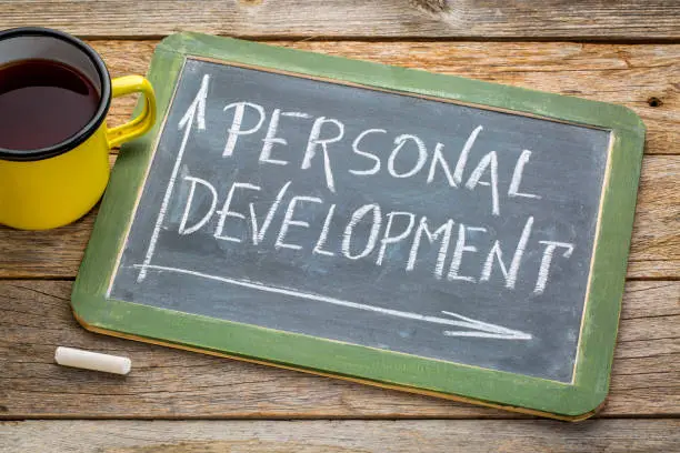 personal development concept - white chalk drawing on a blackboard with cup of tea on a rustic wooden table