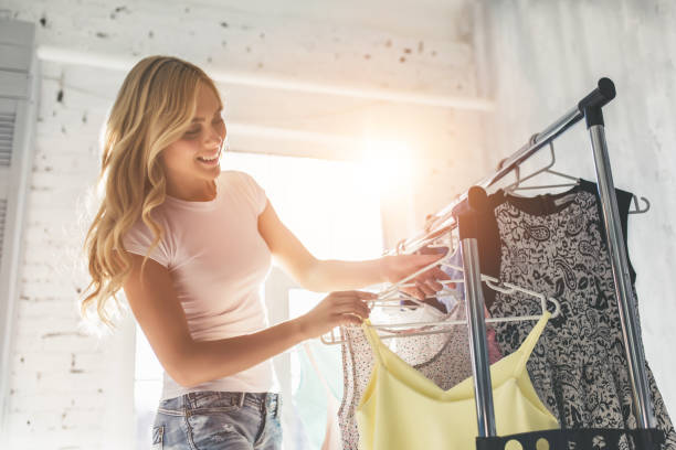 młoda kobieta wybierająca ubrania - clothing closet hanger dress zdjęcia i obrazy z banku zdjęć