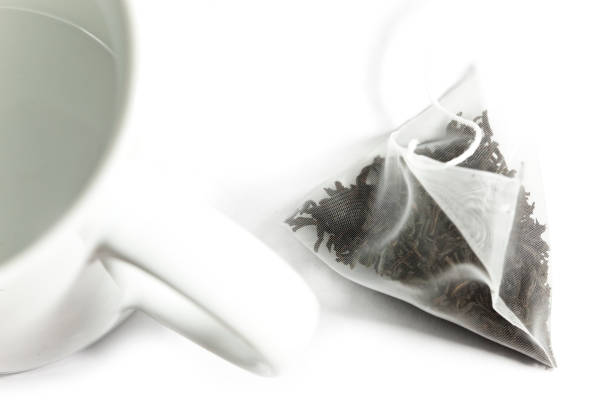 istock Single bag of elite tea in silk fabric packing and tea mug. Small depth of sharpness. 918673994