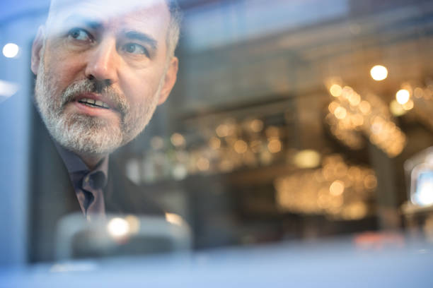 istock Mature Man Using Mobile Phone and Looking Thru Window While Sitting in Bar 918674128