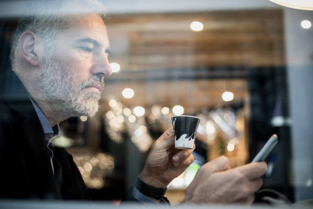 istock Businessman Sitting in a Bar, Drinking Coffee and Using Mobile Phone 918674146