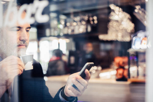 istock Businessman Sitting in a Bar, Drinking Coffee and Using Mobile Phone 918674150