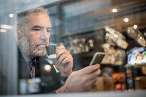 istock Businessman Sitting in a Bar, Drinking Coffee and Using Mobile Phone 918674160