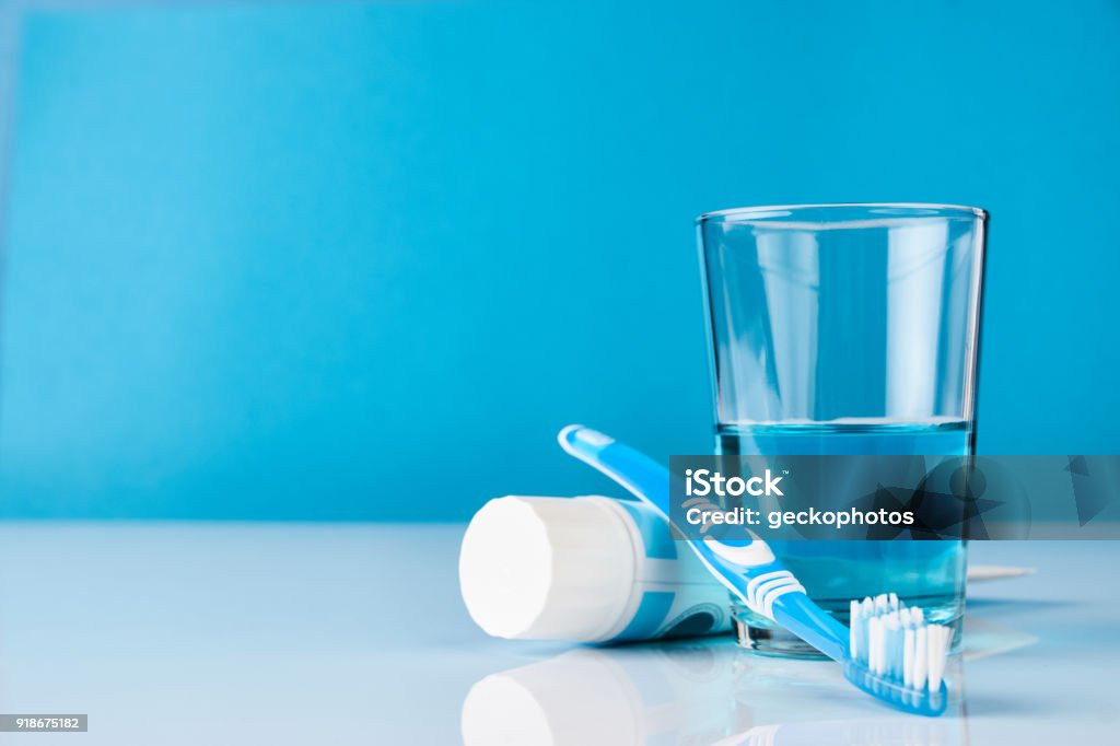 Dental oral hygiene concept A blue toothbrush with toothpaste and glass of blue mouthwash on blue background with copy space, close-up. Dental oral hygiene concept Mouthwash Stock Photo