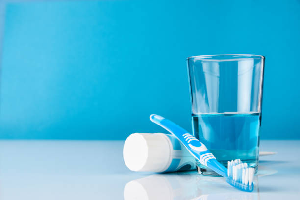 Dental oral hygiene concept A blue toothbrush with toothpaste and glass of blue mouthwash on blue background with copy space, close-up. Dental oral hygiene concept toothbrush stock pictures, royalty-free photos & images