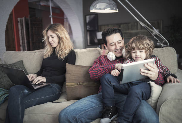 istock Mother working with laptop while father and son are using tablet at home 918696056