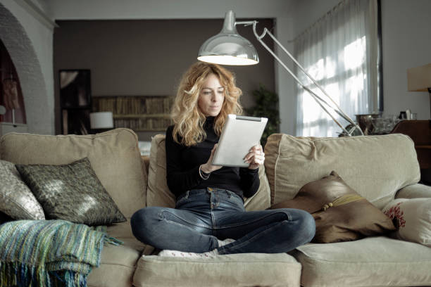 istock Woman using digital tablet in her living room at home 918696080