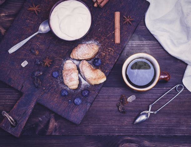 a cup of black tea, croissants and yogurt