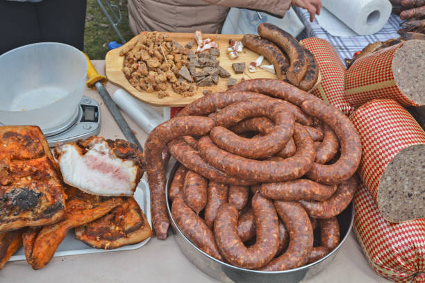 Close-up of raw smoked sausages arranged in a metal tray, ready for grilling or cooking. Traditional meat product, ideal for BBQ and culinary use.