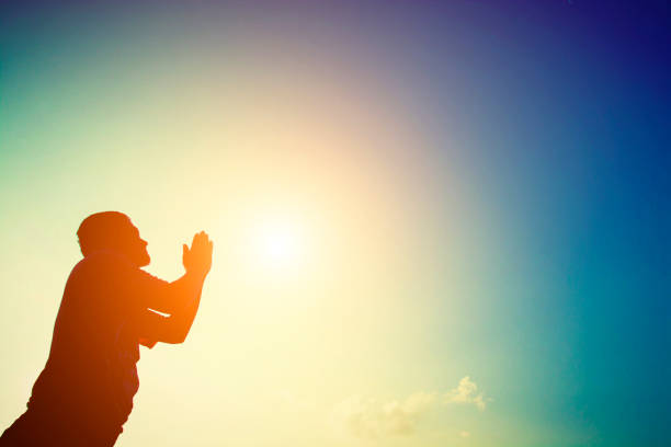 Silhouette of man praying at sunrise.