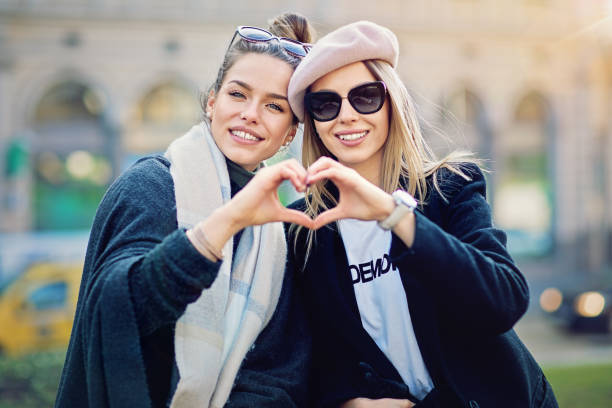 two girlfriends are making heart with their hands on the street - city symbol usa autumn imagens e fotografias de stock