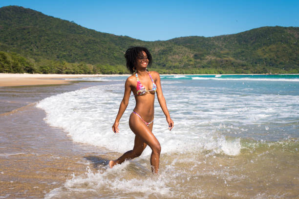 Happy and Playful Beautiful Young Woman in Bikini Playing in Waves at the Beach.