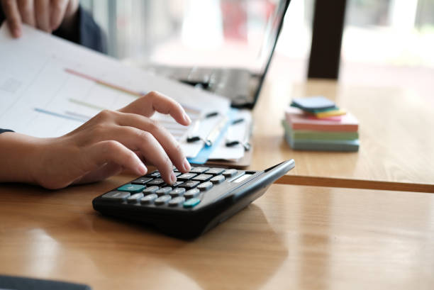 istock financial adviser working with calculator & computer at office. accountant doing accounting & calculating revenue & budget. bookkeeper making calculation. finance & economy concept 918734154