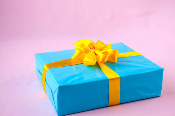 istock Gift in a blue box with an yellow bow on a pink background 918736476