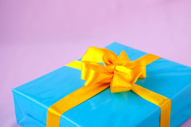 istock Gift in a blue box with an yellow bow on a pink background 918737218